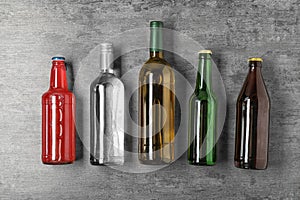 Bottles with different alcoholic drinks on grey background