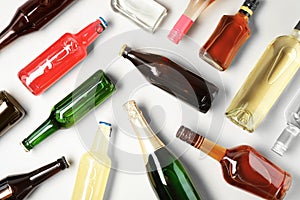 Bottles with different alcoholic drinks on light background