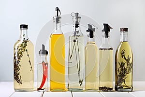 Bottles of different cooking oils on white wooden table against light background