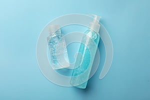 Bottles with different cosmetic gels on light blue background, flat lay