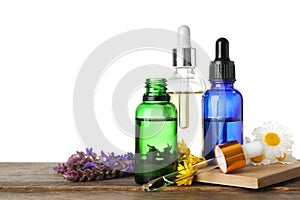 Bottles of different essential oils and wildflowers on wooden table