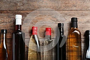 Bottles with different kinds of vinegar and space for text on wooden background