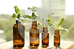 Bottles of essential with and fresh herbs on wooden table indoors