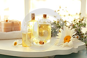 Bottles of essential oil with chamomile flowers on white board