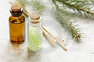 Bottles of essential oil and fir branches for aromatherapy and spa on white table background