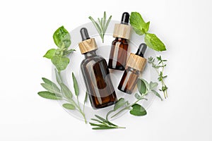 Bottles of essential oil and fresh herbs on white background, flat lay