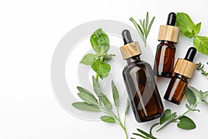 Bottles of essential oil and fresh herbs on white background, flat lay. Space for text