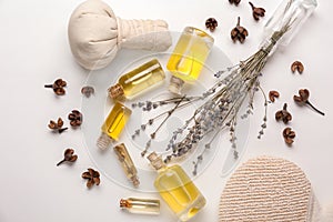 Bottles with essential oil, herbal bag and dry lavender on white background