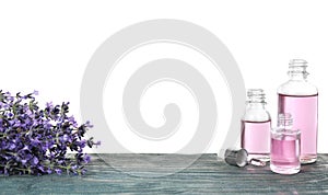 Bottles of essential oil and lavender flowers on blue  table against white background