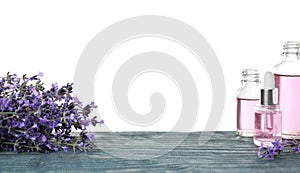 Bottles of essential oil and lavender flowers on blue wooden table