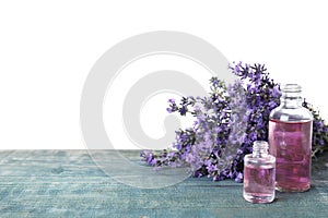 Bottles of essential oil and lavender flowers on blue wooden table