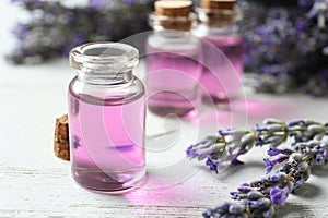 Bottles with essential oil and lavender flowers on wooden table