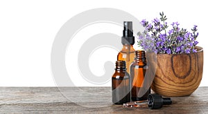 Bottles of essential oil and  with lavender flowers on wooden table against white background