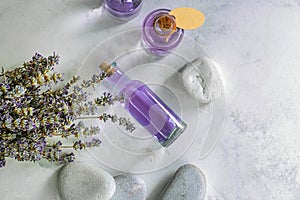 Bottles of essential oil with lavender and spa stones on table