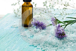 Bottles essential oil and sea salt on a blue wooden table, Spa