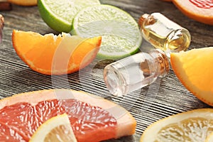 Bottles with essential oils and citrus fruits on wooden background