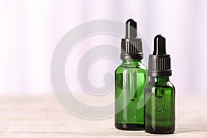 Bottles of essential oils on table against light background. Cosmetic products