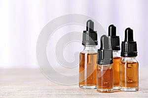 Bottles of essential oils on table against light background, space for text.