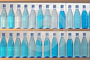 Bottles filled with water, standing on the shelf photo