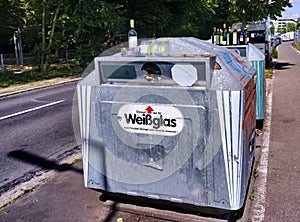 Bottles on a glass container for used glass on the roadside