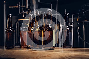 Bottles and glass of craft beer on wooden bar counter at the indie brewery.