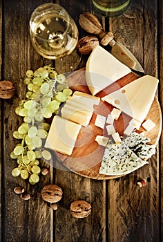 Bottles and glass of white wine, cheese, nuts and grapes