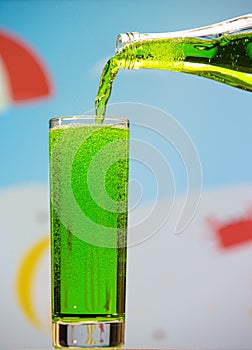 Bottles and glasses with tarragon carbonated drink on summer background