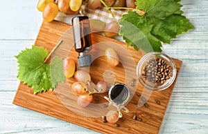 Bottles with grape seed oil on wooden board, top view