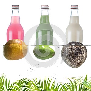 Bottles with grapefruit carbonated drink, coconut milk and avocado juice. Tropical fruits in the water.