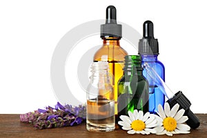 Bottles of herbal essential oils and wildflowers on table, white background