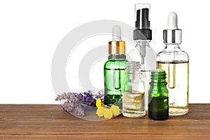 Bottles of herbal essential oils and wildflowers on wooden table