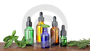 Bottles of herbal essential oils on wooden table