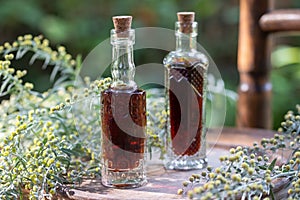 Bottles of herbal tincture with blooming wormwood plant