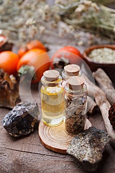 Bottles with herbs, dry flowers, stones and magic objects on witch wooden table.