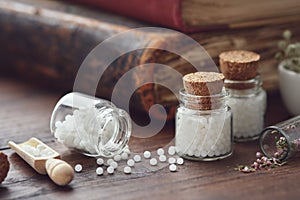 Bottles of homeopathic globules and old books. Homeopathy medicine concept