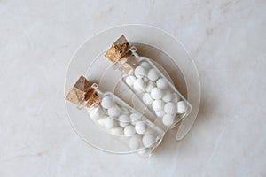 Bottles with homeopathic remedy on white table, flat lay