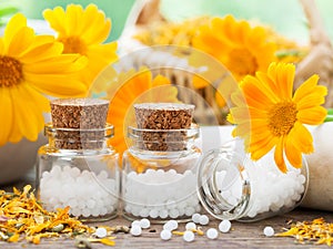 Bottles of homeopathy globules and marigold flowers.