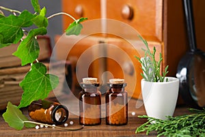 Bottles of homeopathy granules, cabinet with homeopathic remedies and old books on background. Homeopathy medicine