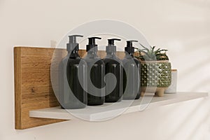 Bottles of hygiene products and houseplant on shelf in bathroom