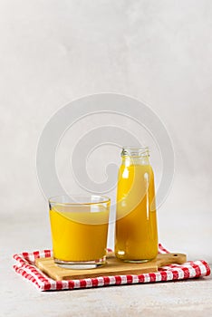 Bottles of Juice for Healthy Diet Autumn Pumpkin Juice in Bottle and Glass Wooden Tray Gray Background Vertical