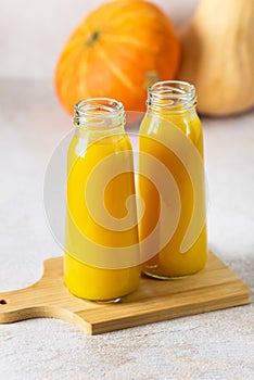 Bottles of Juice for Healthy Diet Autumn Pumpkin Juice Wooden Tray Gray Background Vertical