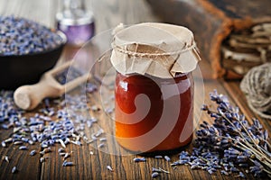 Bottles of lavender salve, balm or cream, lavender flowers, book and essential oil bottle on table. Herbal medicine