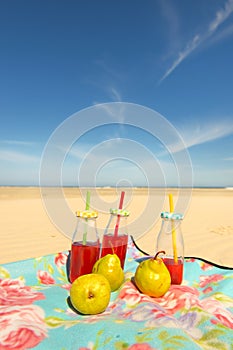 Bottles lemonade and fruit at beach