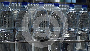 Bottles of mineral water move in a continuous stream along the conveyor. Production of drinking water at a food processing plant