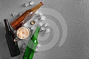 Bottles and mug with cold beer on textured background