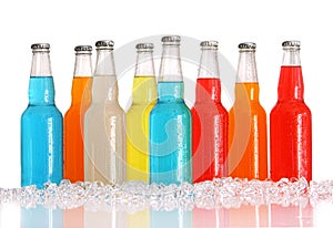 Bottles of multi-color drinks with ice on white