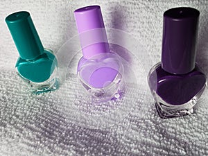 bottles with nail polish in aquamarine, pink and purple, with white background towel photo