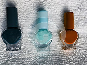 bottles with nail polish in dark blue, light blue and orange, with white background towel photo