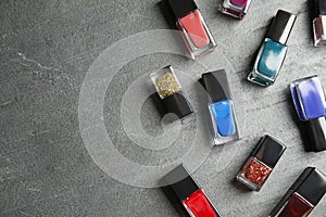 Bottles of nail polish on grey background, top view
