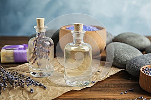 Bottles with natural herbal oil and lavender flowers on table